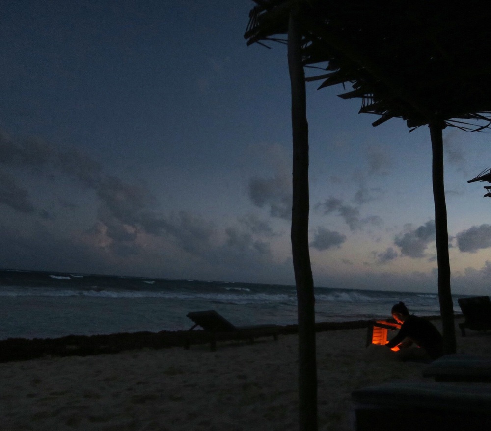  a beach goer keeps her fire going on the Tulum beach 